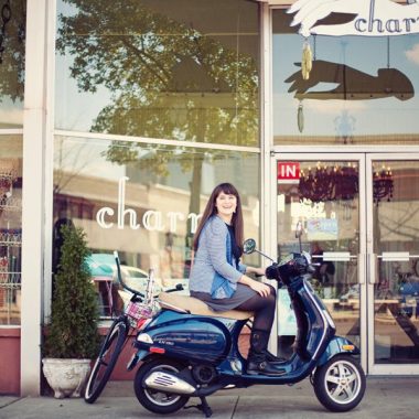 carrie rollwagen sitting on a scooter in front of the jewelry store charm
