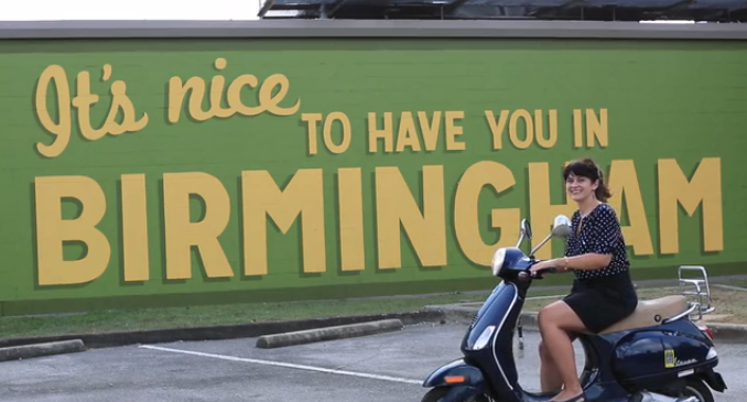 carrie rollwagen driving a vespa in front of birmingham mural