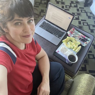 girl in a hotel room with a laptop and a snack